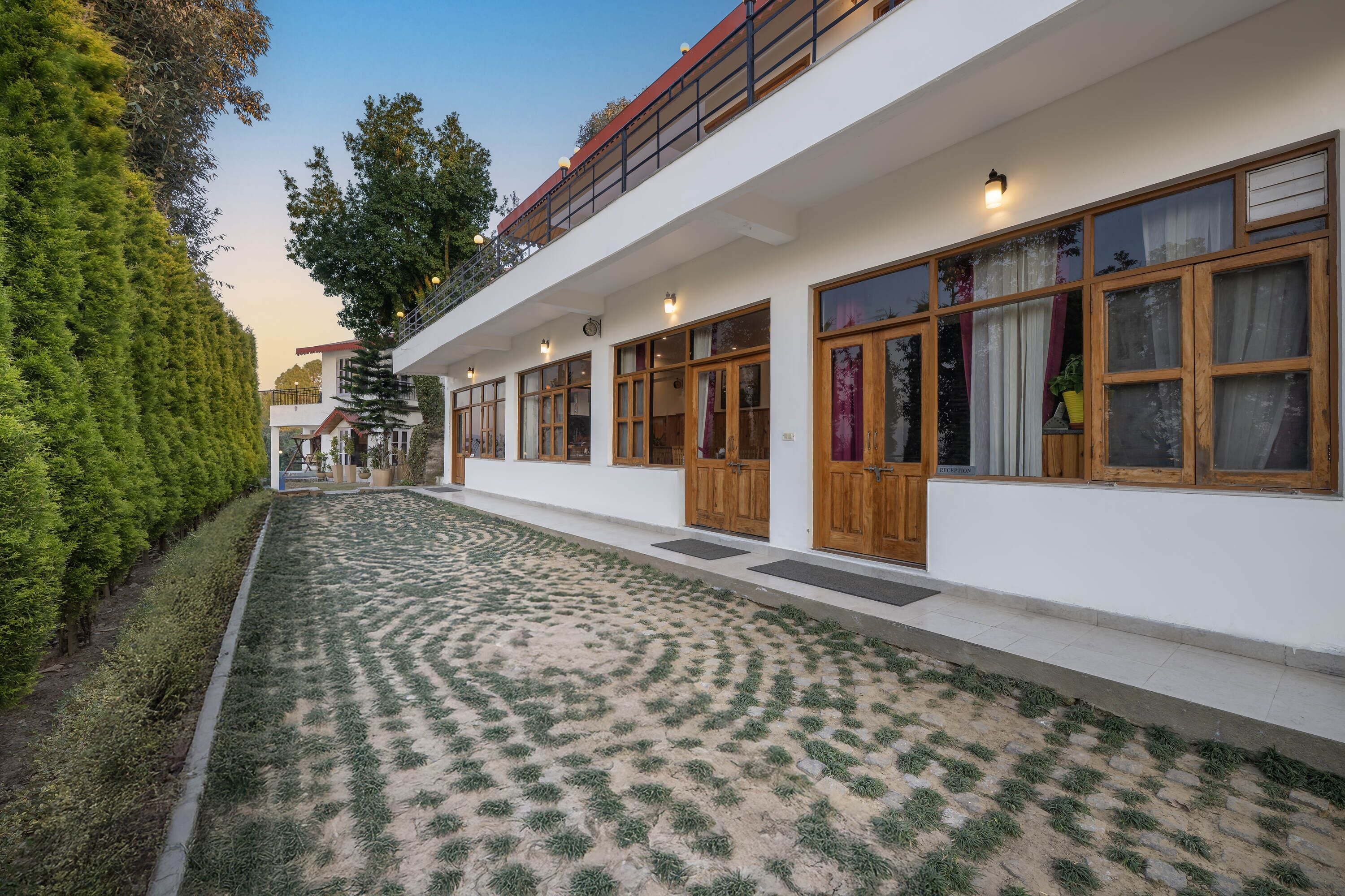 Un edificio moderno con una galería techada, amplias ventanas y un jardín cuidado.