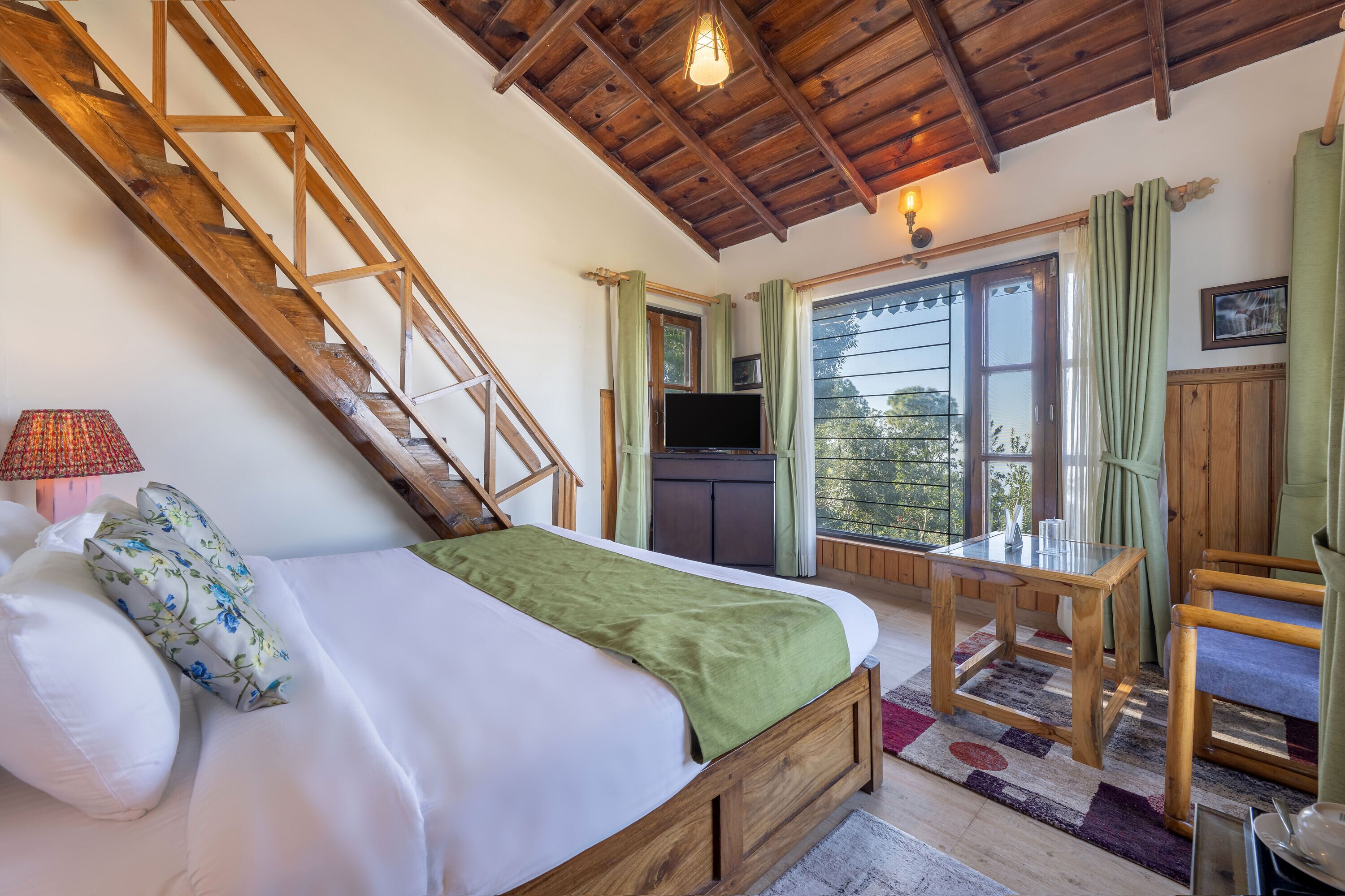 Ein Schlafzimmer mit einem hölzernen Bett, einem Schreibtisch, einem Stuhl, einem Fernseher und einer Treppe.