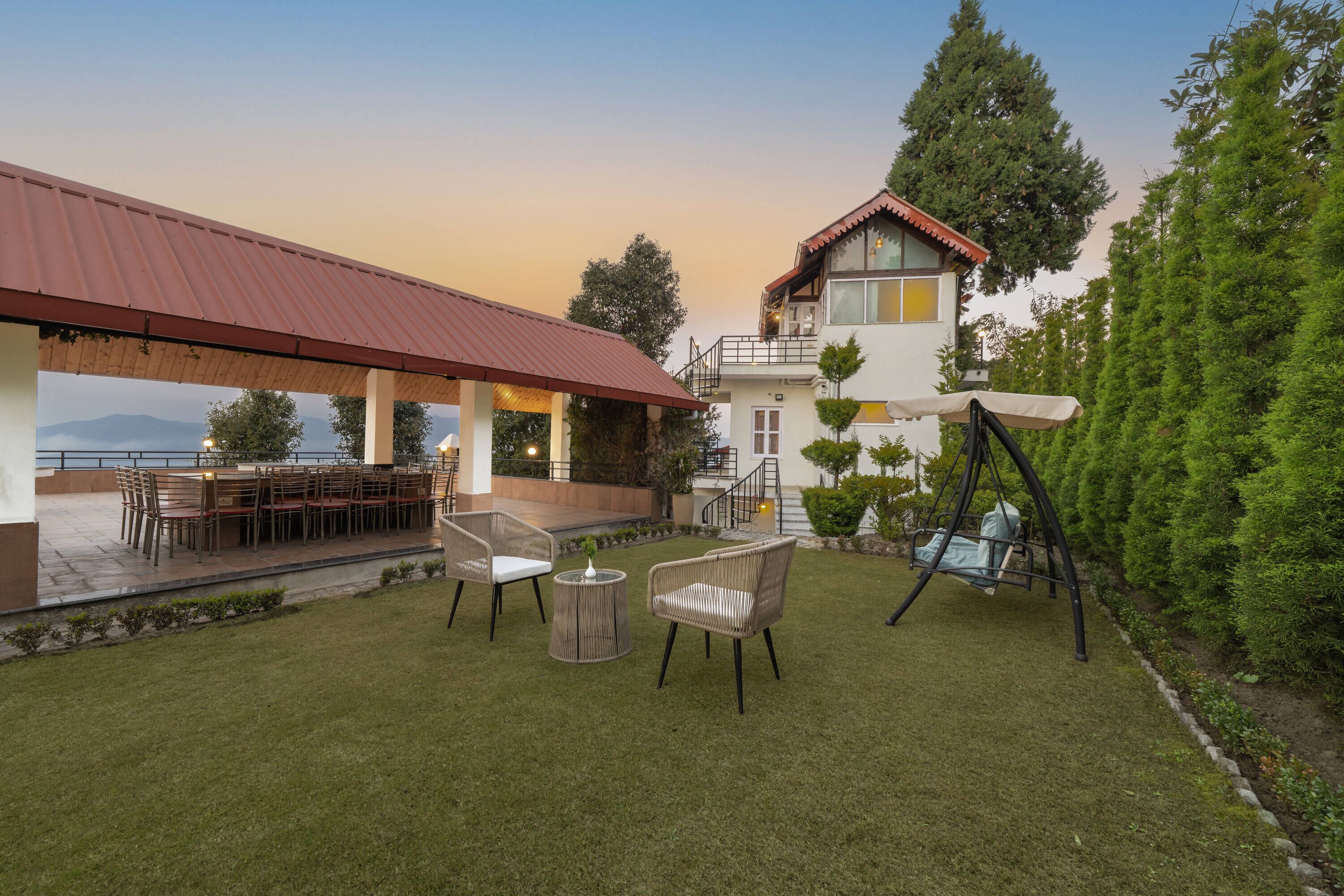 A patio area with a dining table and chairs, a swing, and a view of the mountains.