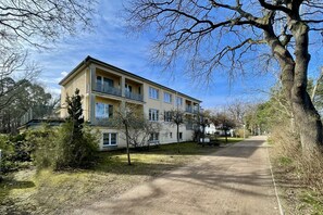 Un edificio a più piani con balconi, immerso nel verde sotto un cielo sereno.