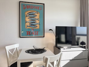 Un coin repas agrémenté d’une affiche encadrée, d’un téléviseur et d’une table avec des chaises.