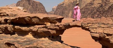 A person standing on a rock formation with a natural archway.