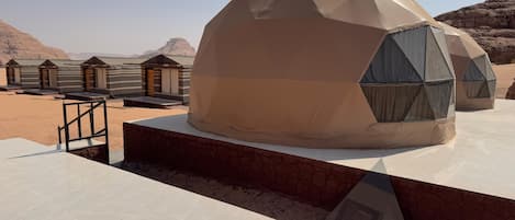 A desert-themed accommodation with dome-shaped structures, a tiled floor, and a view of the surrounding landscape.