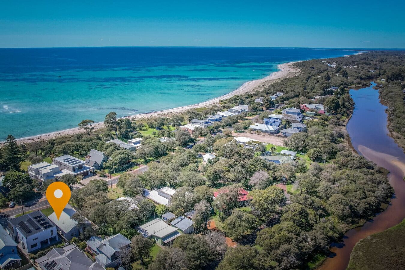 Vista aérea de una zona residencial costera con casas, una playa y un río.