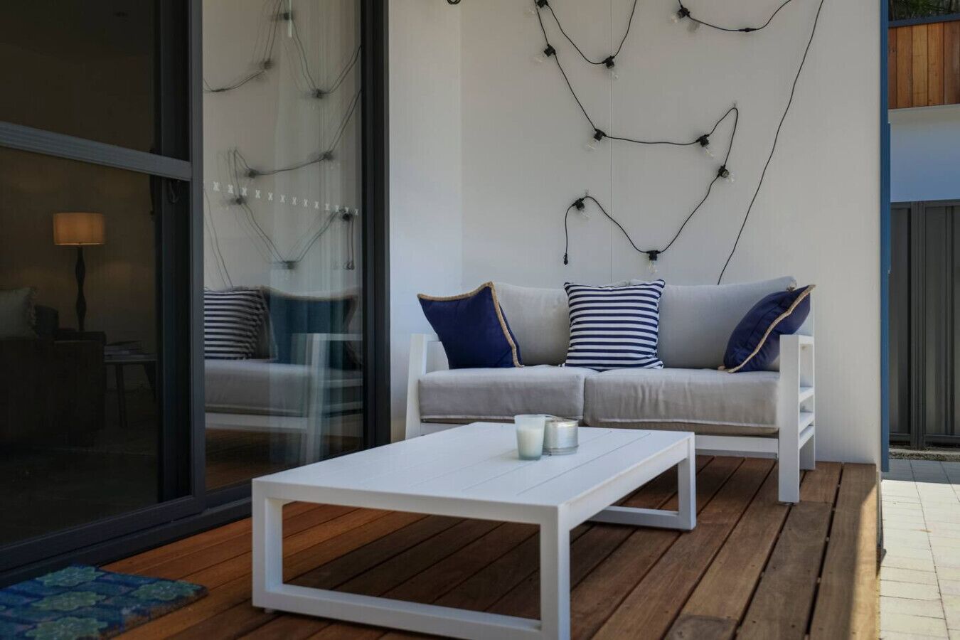 A modern living room with a white sofa, striped pillows, and a white coffee table.