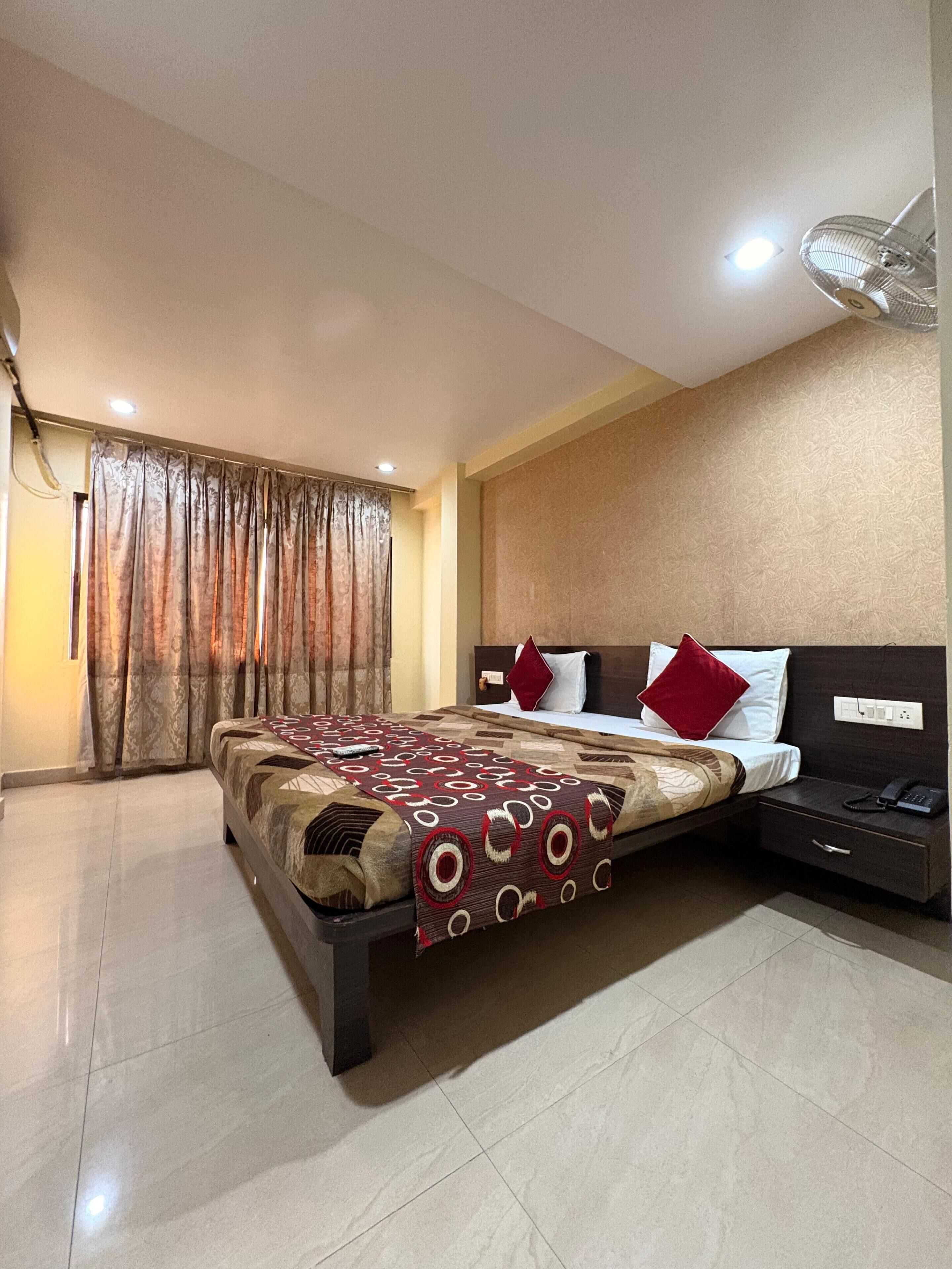 A hotel room with a bed, a nightstand, a telephone, and a ceiling fan.
