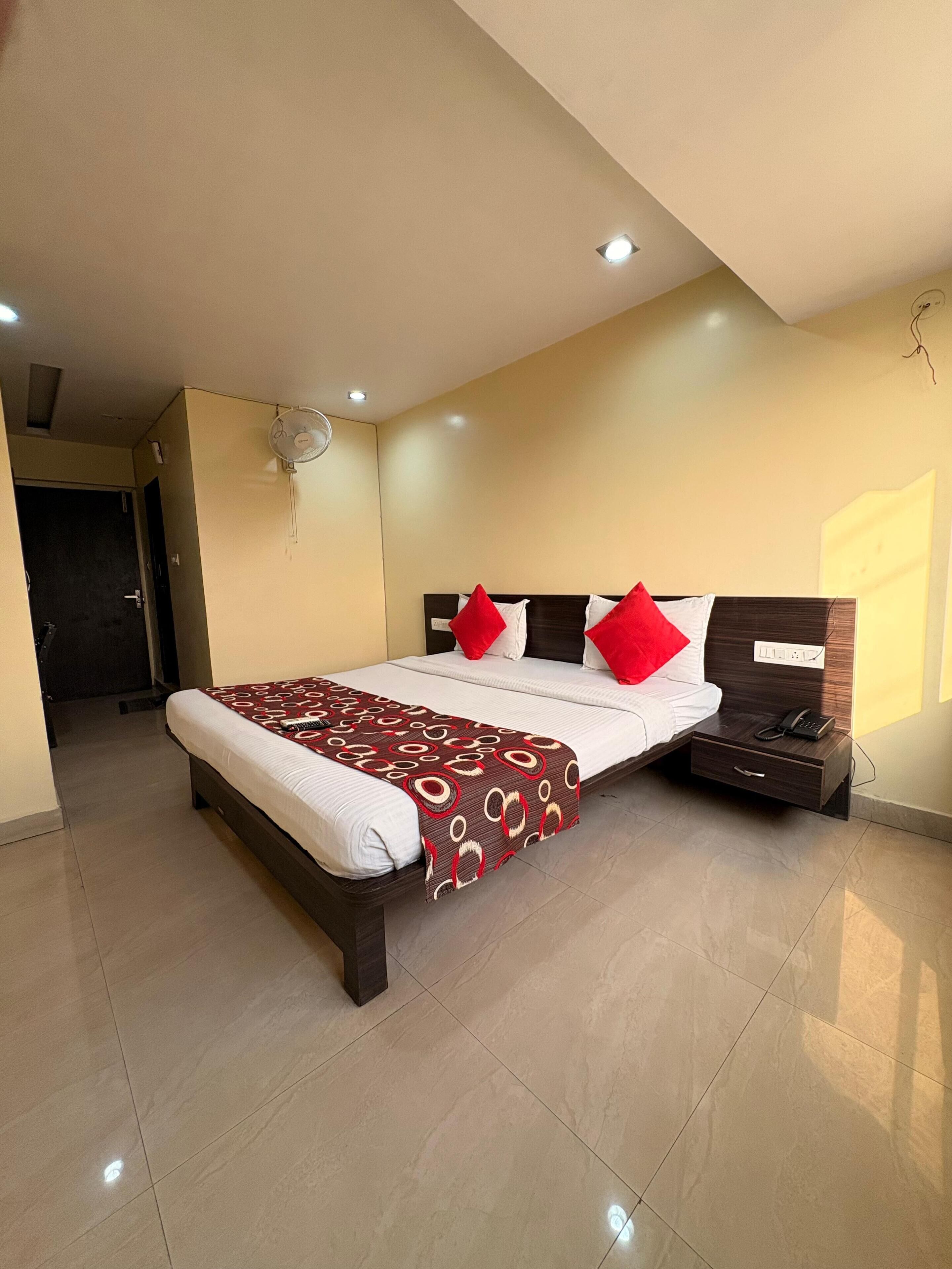 A modern bedroom with a bed, bedside table, and a wall-mounted fan.