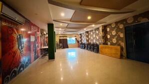 A spacious hall with a high ceiling, patterned walls, and rows of chairs. - Hotel Welfare Club (Bhilai)