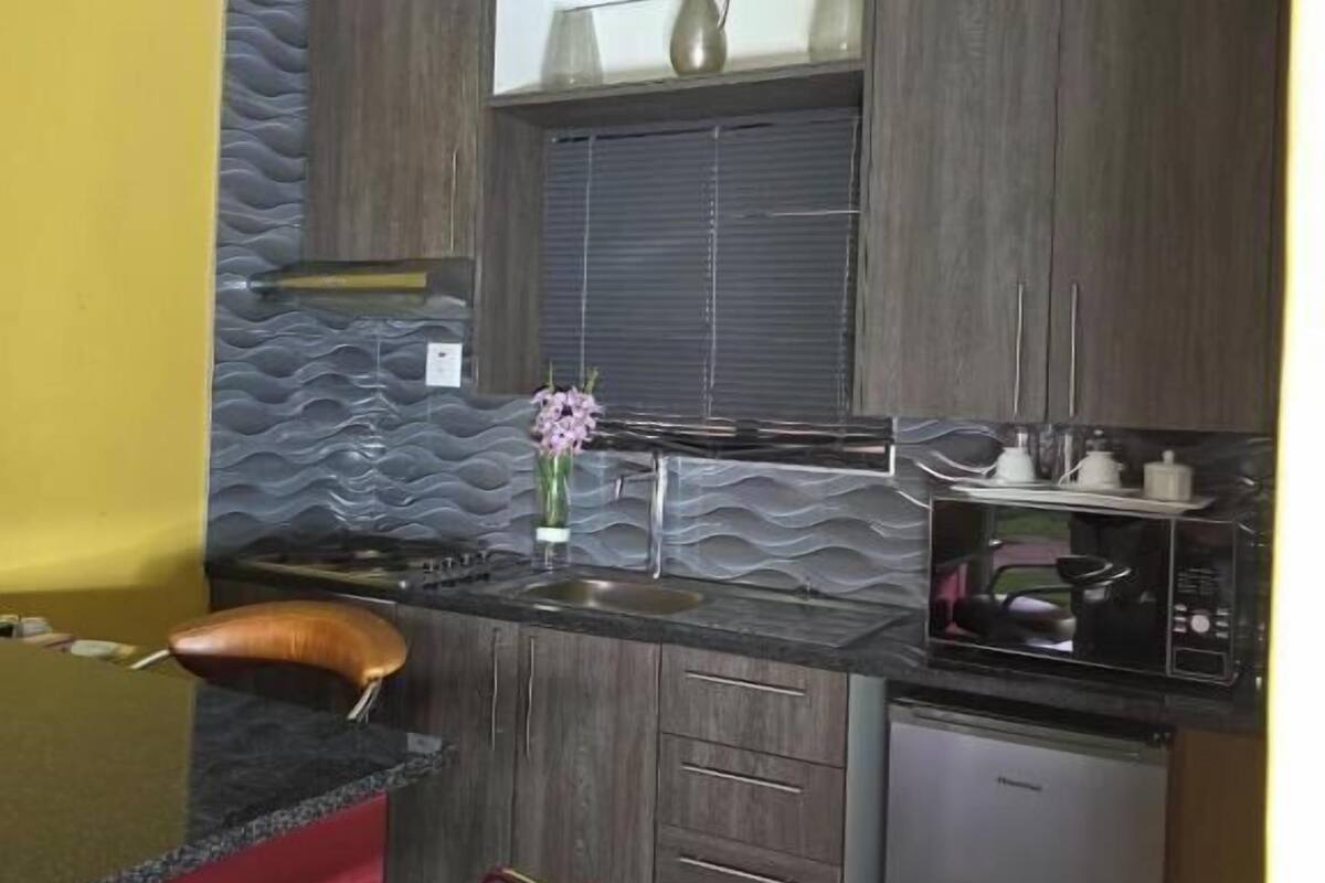 Eine kleine Küche mit dunklen Holzschränken, einer eingebauten Mikrowelle und einem kleinen Kühlschrank.