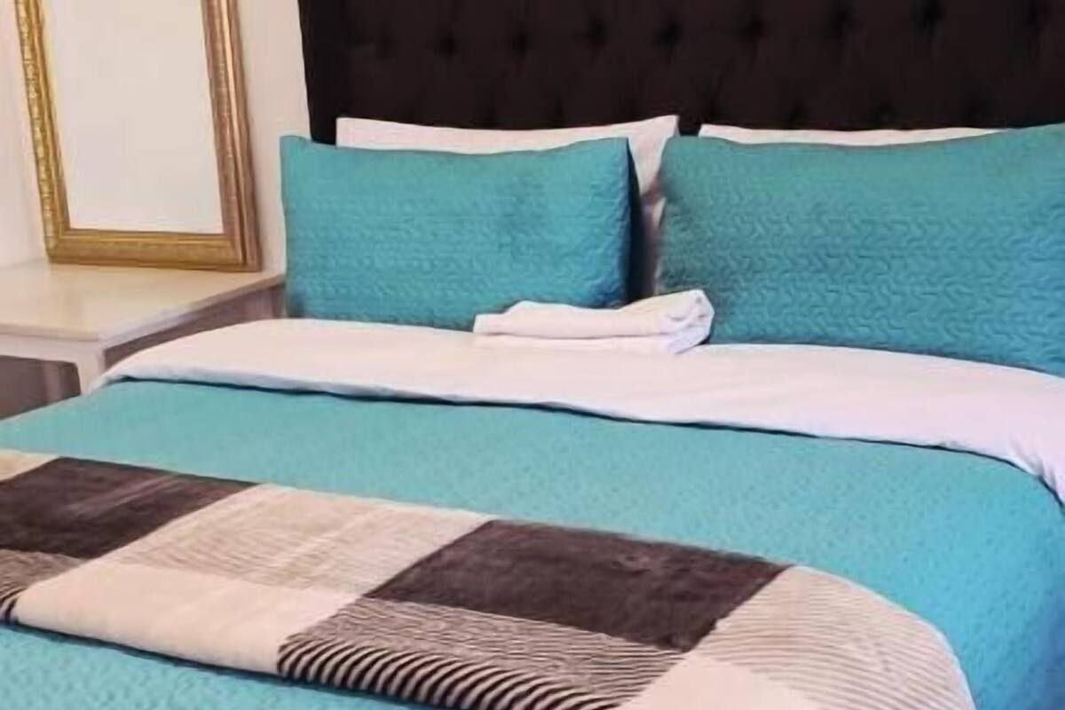 Ein Bett mit einer blauen Steude und einer braun-weißen Patchworkdecke.