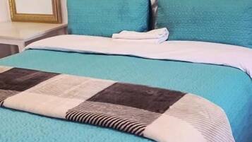 A bed with a blue quilt and a brown and white quilted blanket.