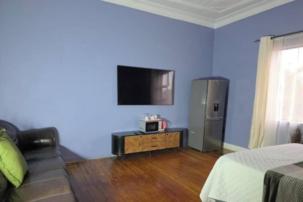 Ein Zimmer mit einem flachbildfernseher an der Wand, einem Kühlschrank, einer Mikrowelle und einem Holzkasten.