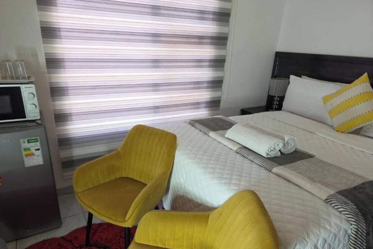 Ein Hotelzimmer mit einem Bett, einem gelben Sessel, einer Mikrowelle und einem Kühlschrank.