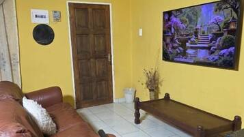 Uma sala de estar com um sofá de couro marrom, um banco de madeira e um quadro com uma cena de jardim na parede.
