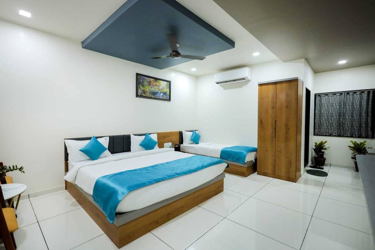 A modern hotel room with a large bed, a ceiling fan, an air conditioning unit, and a wooden wardrobe.