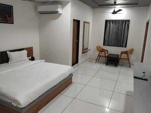 A hotel room with a bed, a desk, a chair, and a small table.