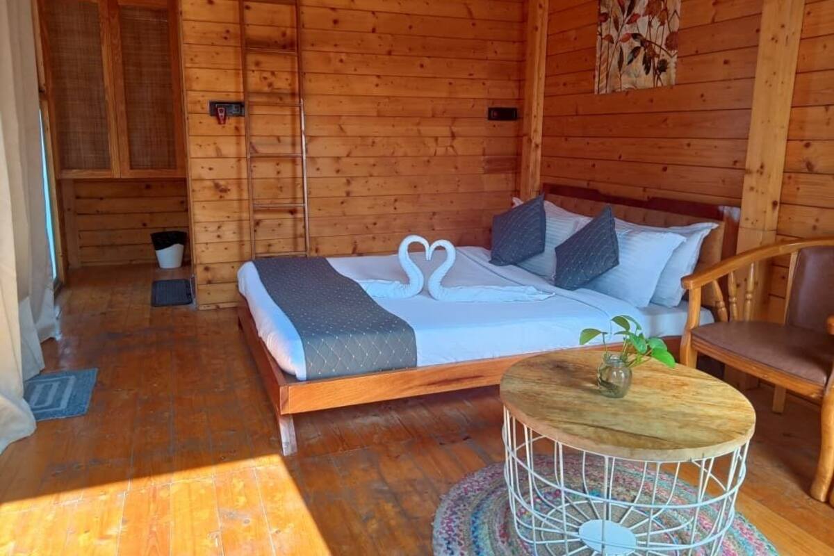 Una habitación de cabaña de madera con una cama, una mesita y una silla.