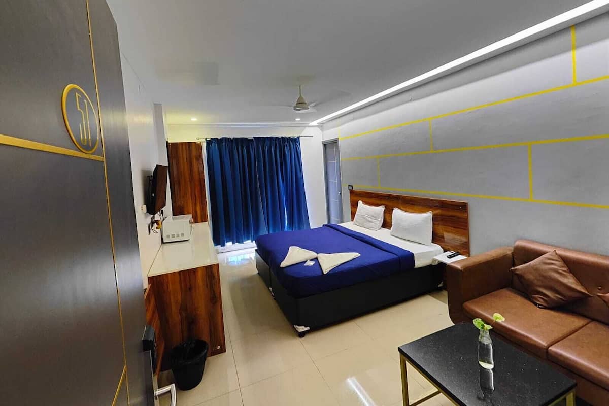 Una habitación de hotel con una cama, un sofá, una mesita y un televisor.