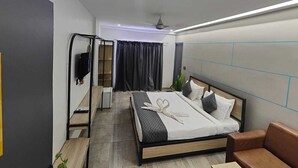 Una habitación de hotel moderna con cama, zona de estar, televisor y armario.