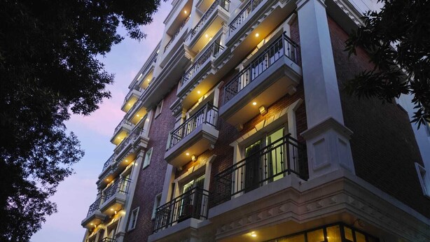 Un hotel de varios pisos con un estilo arquitectónico clásico, que cuenta con balcones en cada planta y amplias ventanas.