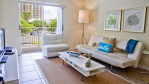 A modern living room with a sofa, a coffee table, a floor lamp, and a TV. - Relaxed 2BR Coastal Haven with Pool, Minutes from the Beach! - (Key Biscayne)