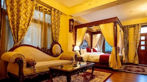 A room with a four-poster bed, a sofa, a coffee table, and a large window with curtains. - The Himalayan Heritage (Shimla)