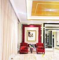 A spacious lobby with a red and white color scheme, two red armchairs, a framed artwork on the wall, and a floral arrangement on a table.