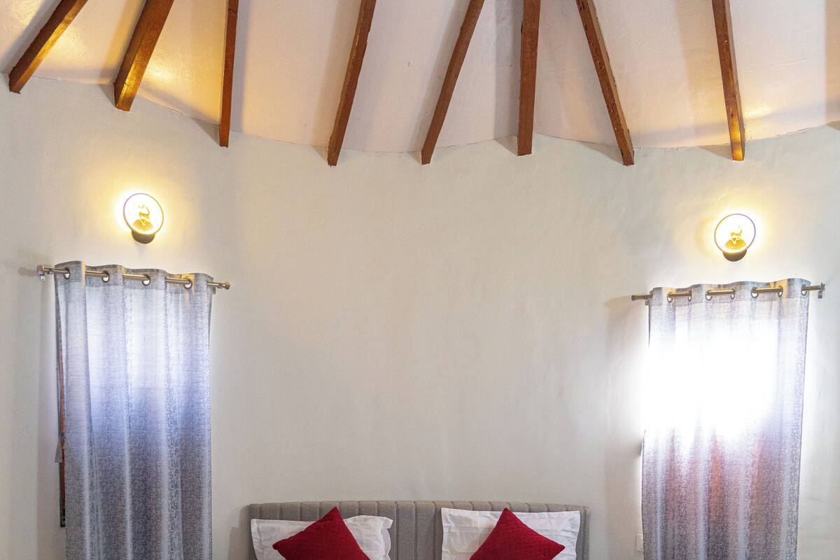 A bedroom with a large bed, two bedside tables, and a ceiling with wooden beams.