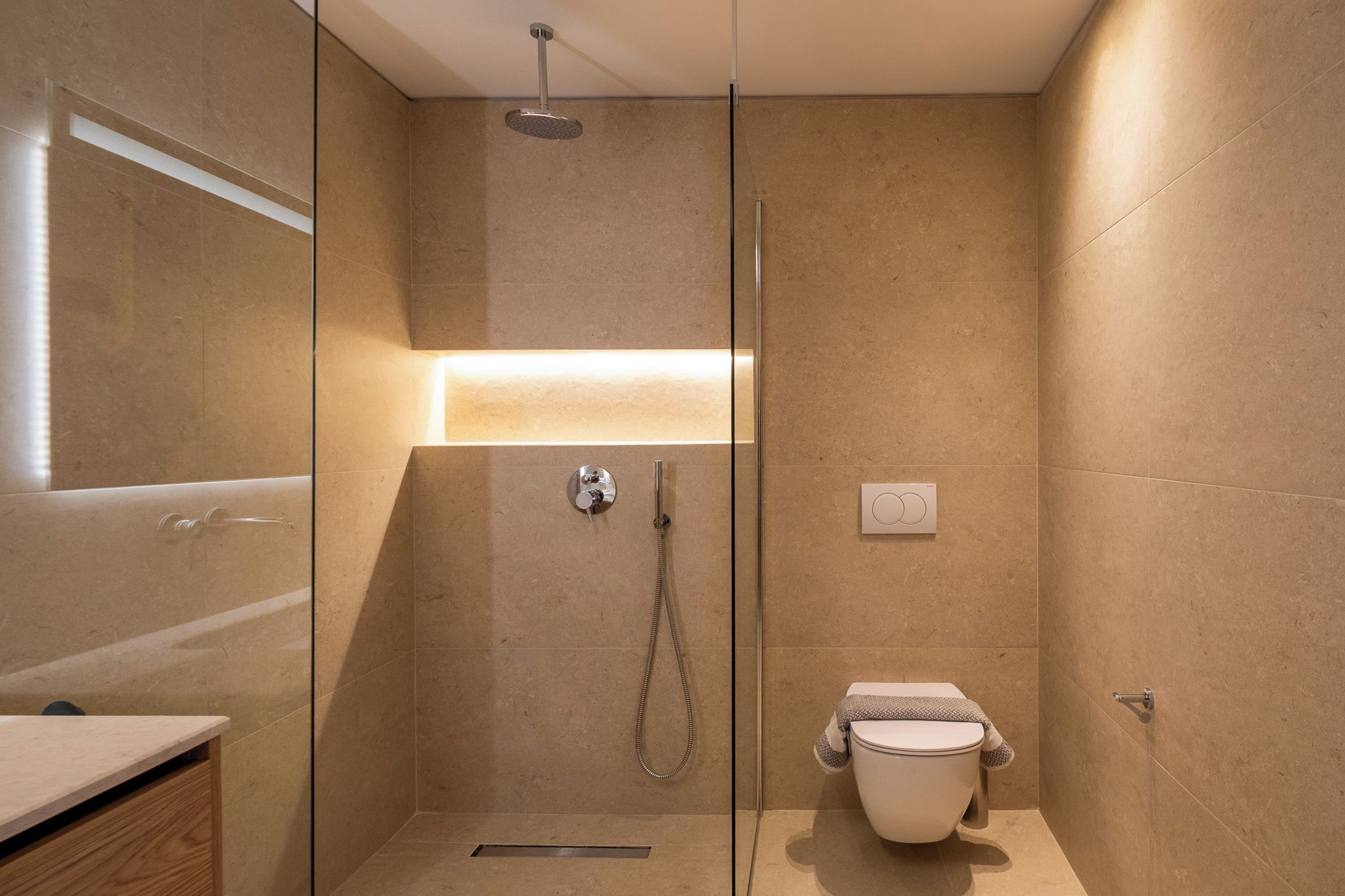 A modern bathroom with a glass-enclosed shower, a toilet, and a vanity with a mirror.