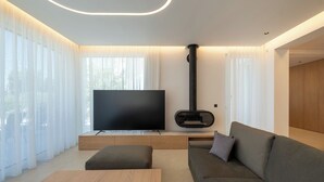 Uma sala de estar moderna com uma TV de tela plana, uma lareira e um sofá.