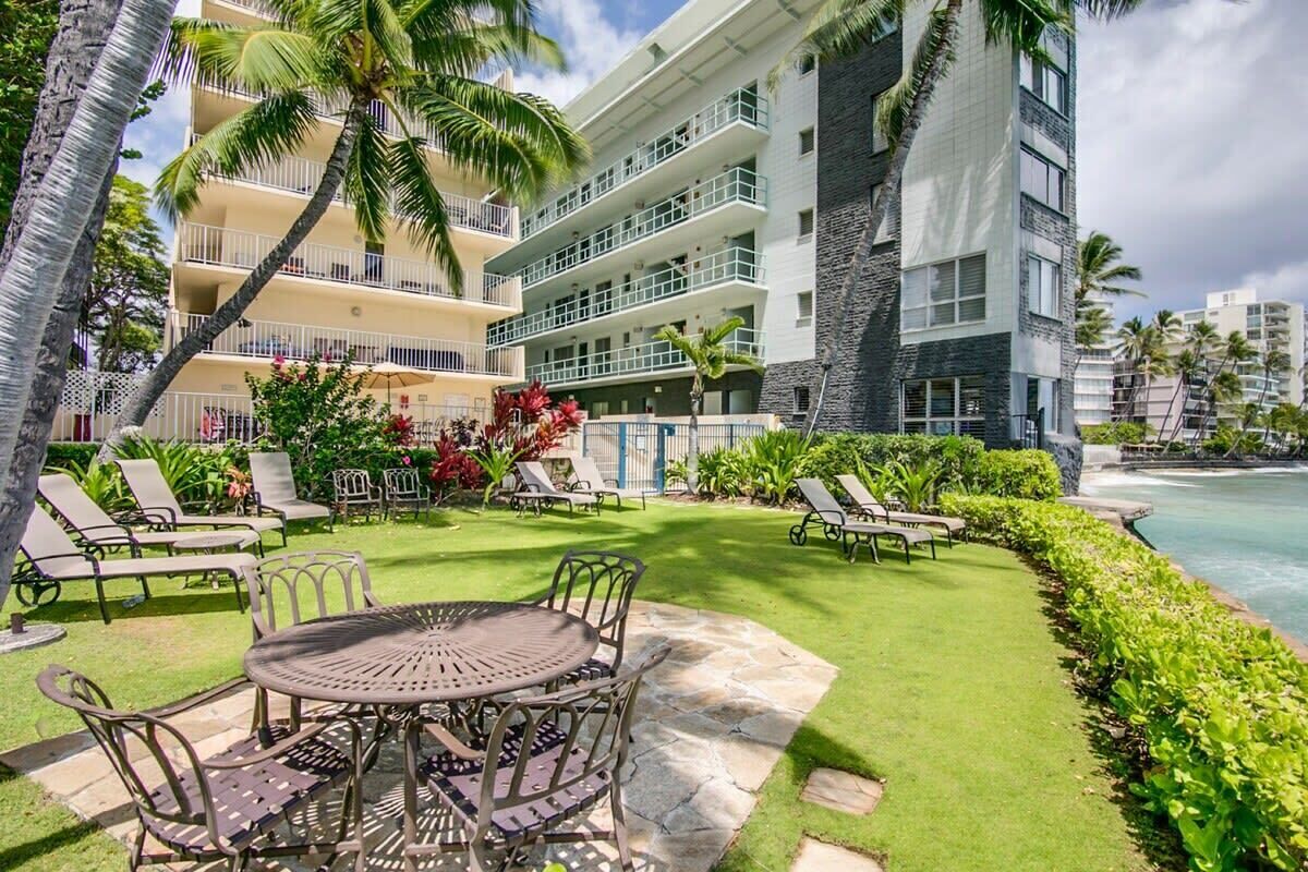 Une cour d’hôtel avec une piscine, des chaises longues et un espace repas.