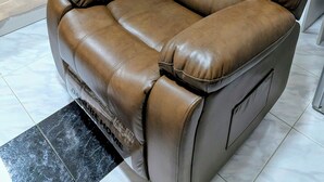 A brown leather recliner chair with a footrest and armrests, positioned next to a bed with a white mattress and a green pillow. - Private Deluxe Studio - Cozy Chic & Fully Equipped (muscat)