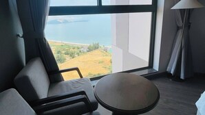 A modern hotel room with a large window offering a view of a coastal landscape.