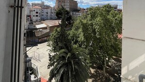 Un balcón con vistas a un paisaje urbano, que incluye edificios y una palmera.