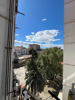Ein Balkon mit Blick auf eine Stadtlandschaft, einschließlich Gebäude und einer Palme.