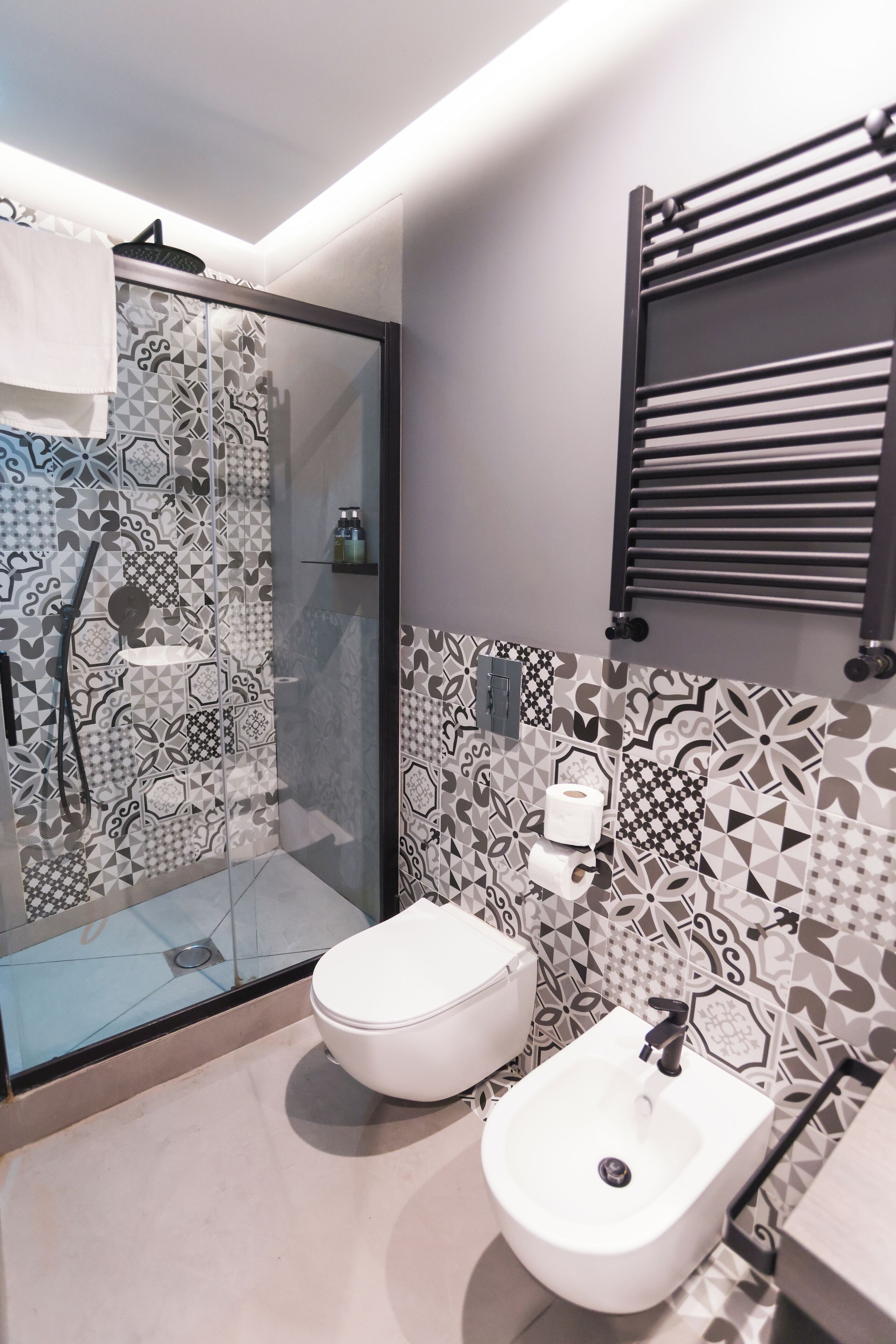A modern bathroom with a glass-enclosed shower, a white toilet, and a bidet.
