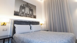 A hotel room with a bed, a nightstand, a lamp, a wall-mounted picture, and a window with curtains. - L'Infinito88 Charmant rooms (Naples)