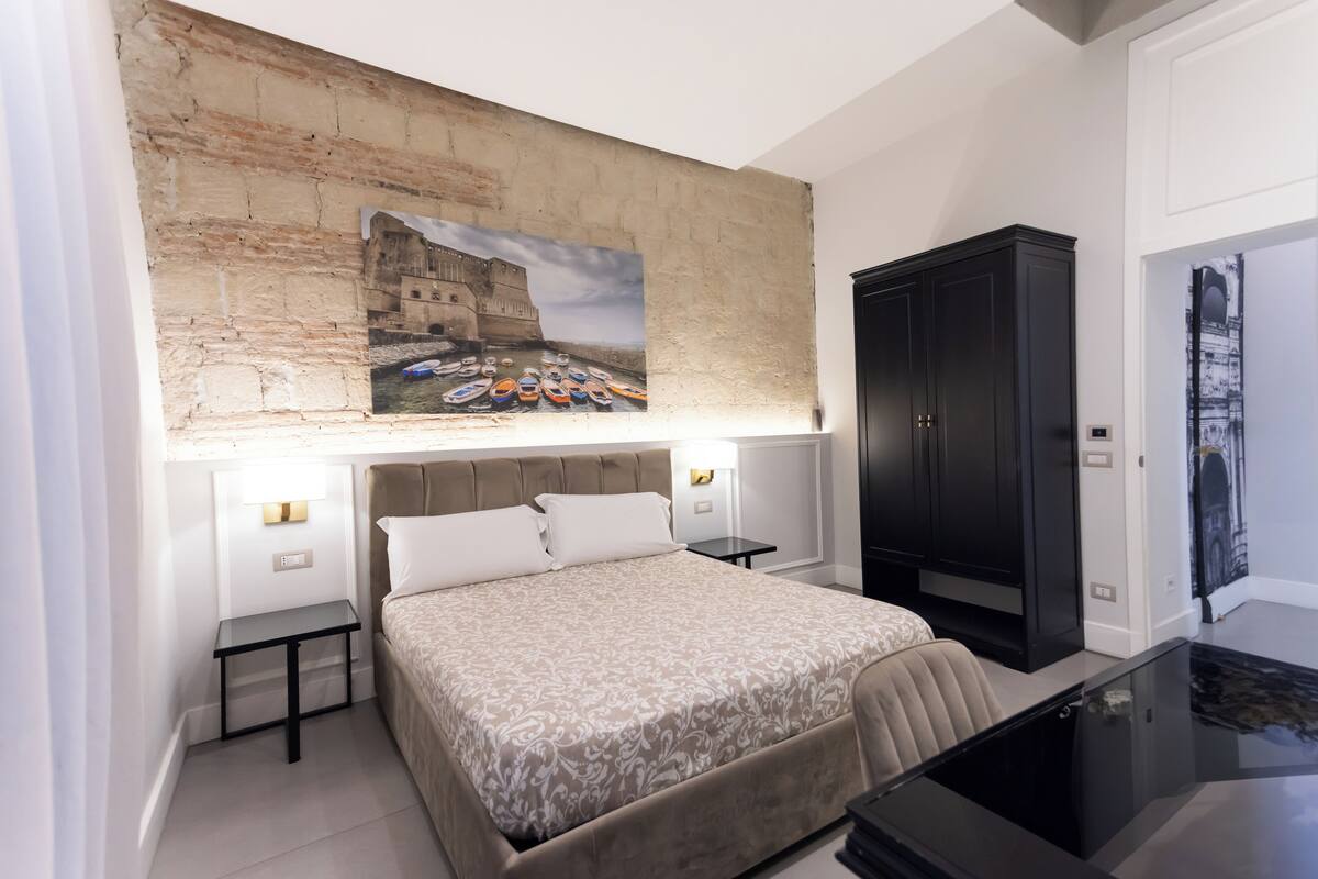 Un dormitorio con cama, mesitas de noche, escritorio y armario.