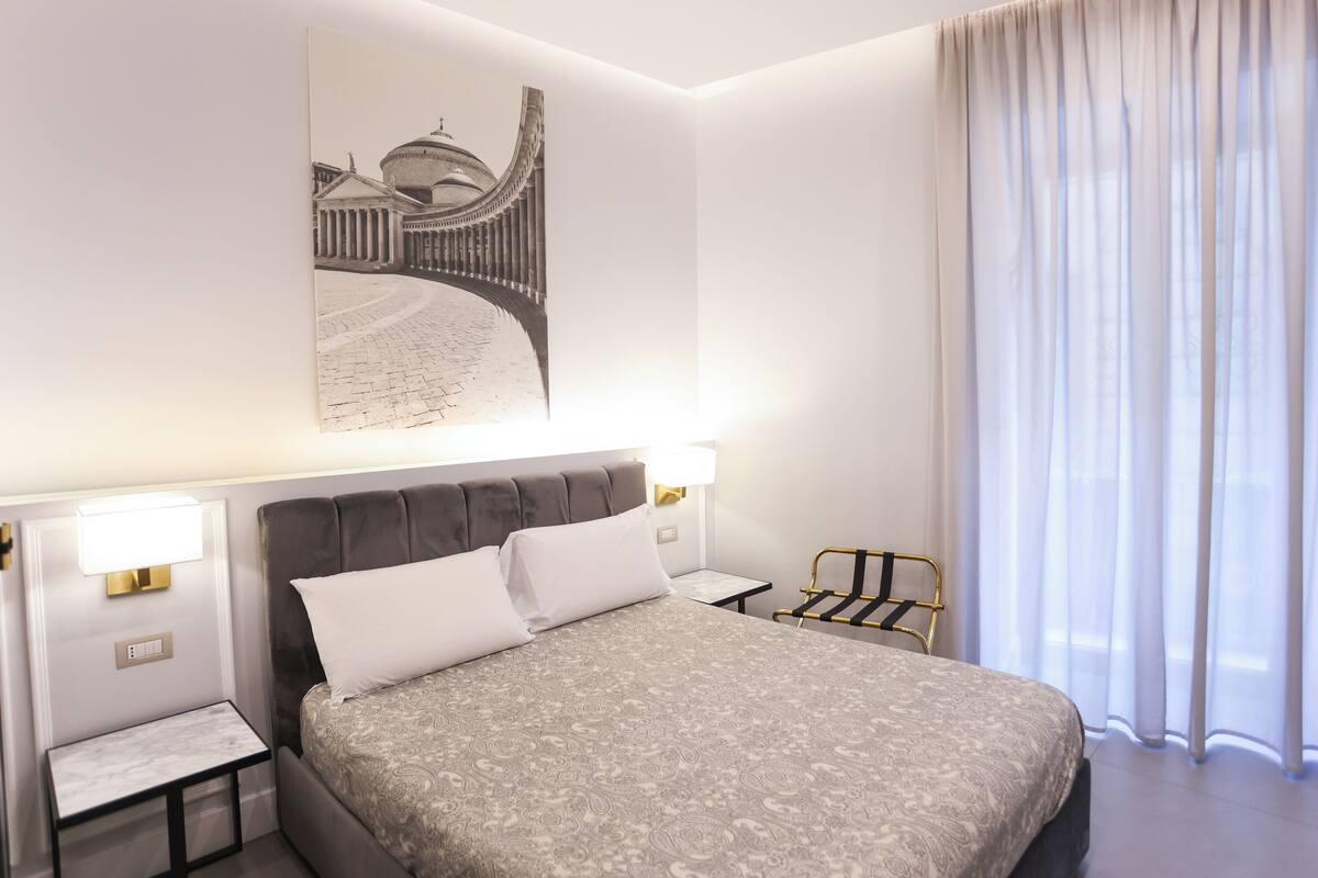 Una habitación de hotel moderna con una cama grande, una mesita de noche, una lámpara y una silla.