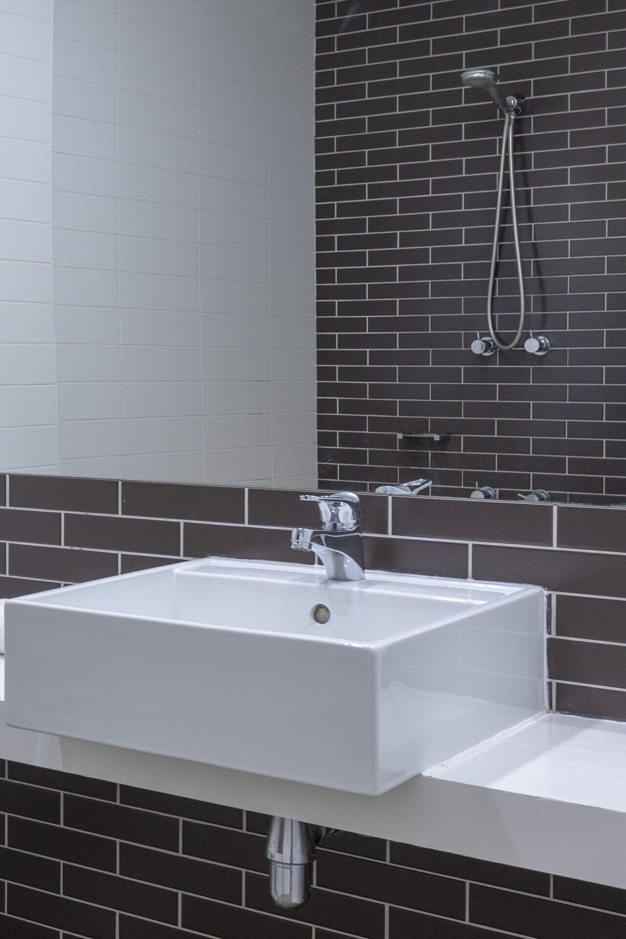 A bathroom with a white sink, a mirror, and a shower.