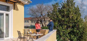 A balcony with a table set for breakfast, a chair, and a person standing. - Maissance (Preveza)