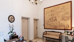 A room with a sofa, a desk with a computer, a large framed painting, and a chandelier. - Maissance (Preveza)