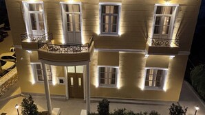 A two-story building with multiple balconies, a central entrance, and a stone pathway leading to the entrance. - Maissance (Preveza)