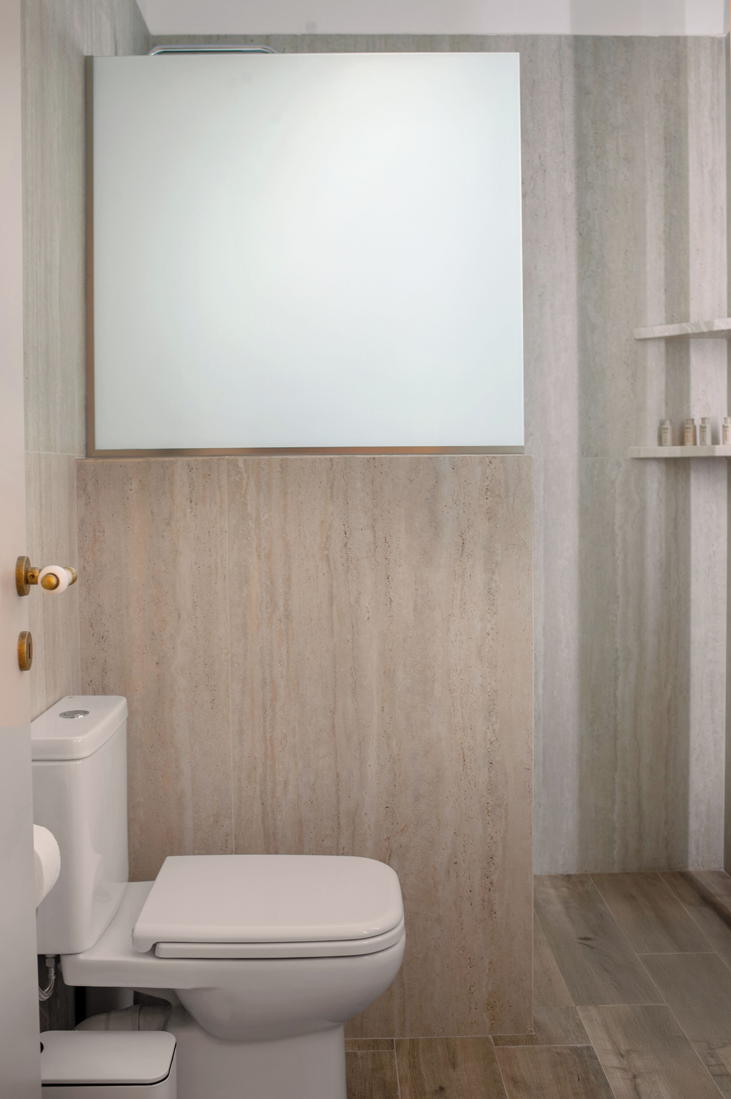 A modern bathroom with a toilet, a wall-mounted mirror, and a shelf with toiletries.