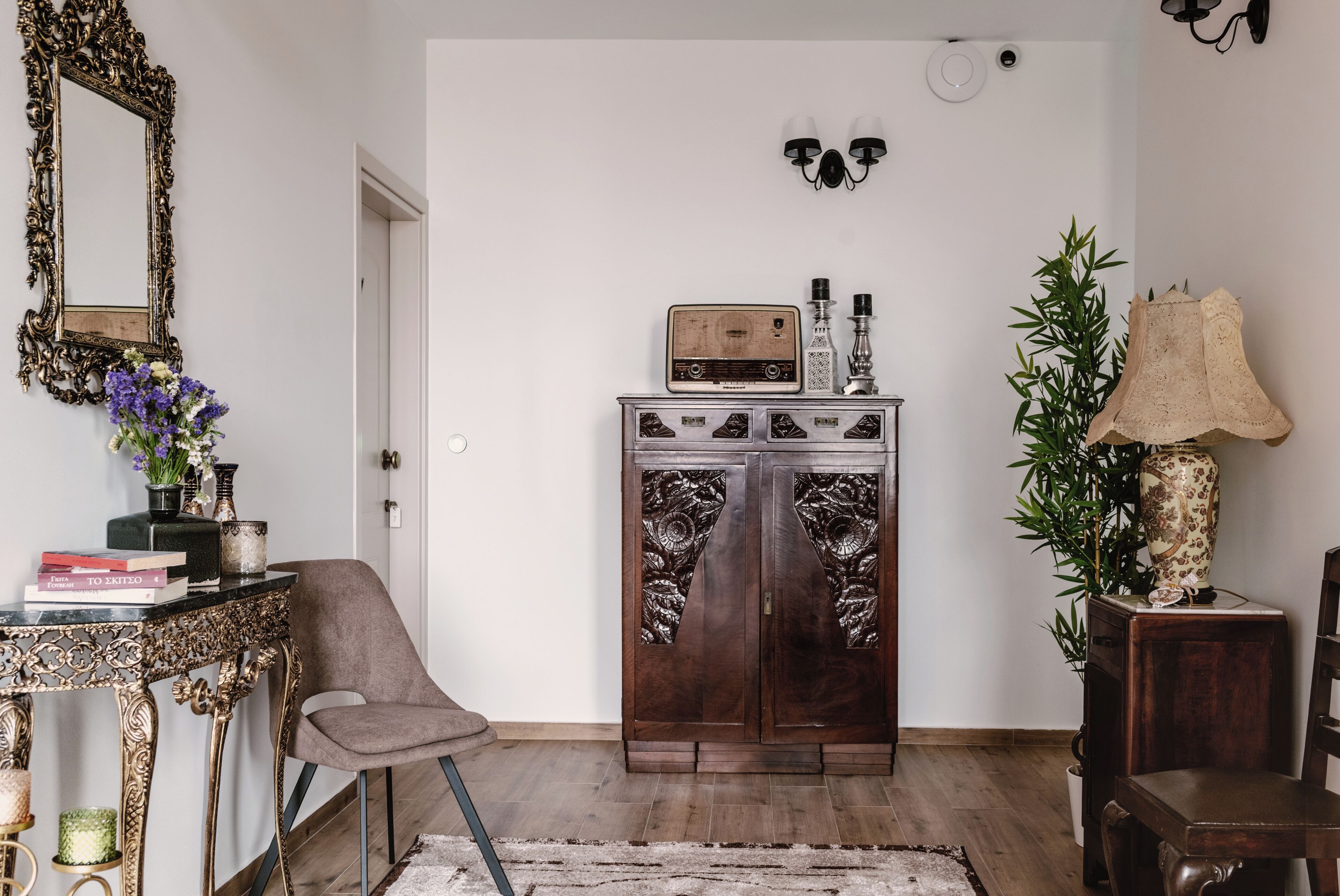 A room with a vintage radio, a cabinet with decorative doors, a chair, a mirror, and a lamp.