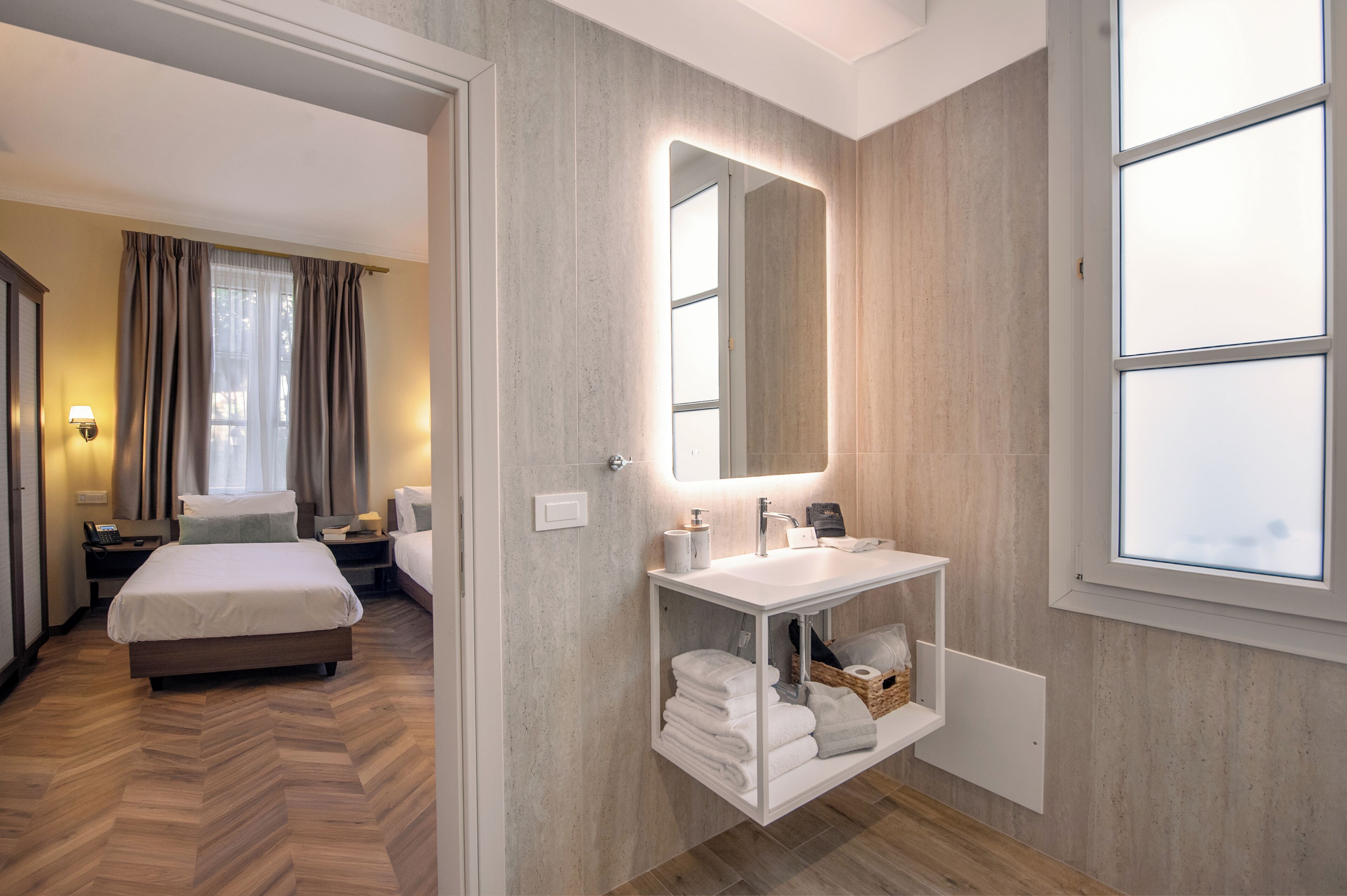 Ein Hotelzimmer mit einem Bett, einem Badezimmer inklusive Spiegel, Waschbecken und Fenster.