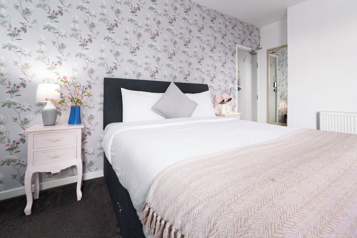 A neatly arranged bedroom with a bed, bedside tables, and a mirror.