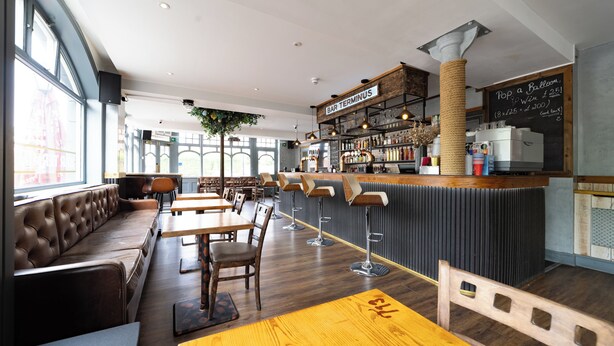 Eine moderne Bar mit Ledersitzgelegenheiten, Holztischen und einer Bar mit einer Kreidetafel-Speisekarte.