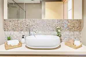 Une salle de bain avec un grand lavabo blanc, un miroir au-dessus et un pare-chocs en mosaïque.