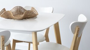 Une table à manger avec six chaises, un panier en osier et une œuvre d’art encadrée accrochée au mur.